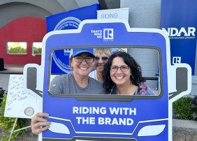 North Dakota REALTORS® Members pose with a Riding with the Brand bus cutout.