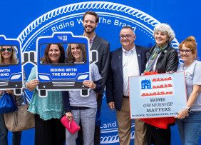 NHAR members pose with RWTB bus cutout photo props and home ownership matters signs.