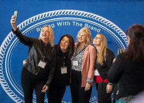 Oregon REALTORS® members pose with the Riding with the Brand backdrop taking a selfie.