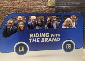 Georgia REALTORS® pose with a Riding with the Brand bus cutout social media prop.