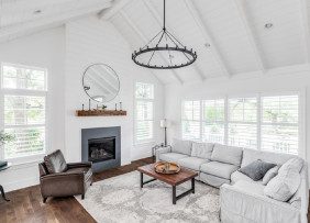 Farmhouse style living room space with fireplace, chandelier, vaulted ceilings
