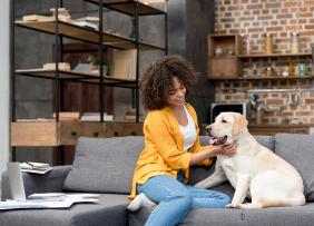 A woman petting a dog on a living room couch