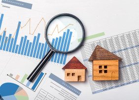 Wooden houses and magnifying glass on spreadsheets