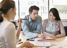 Young couple and businesswoman reviewing papers