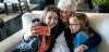 happy grandmother and granddaughters taking selfie
