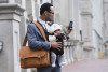 Businessman on the street carrying a briefcase, a phone, and a baby