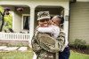 Portrait of female U.S. soldier in uniform with young daughter in front of home