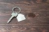 Key on metal keychain with house fob on dark stained wood background