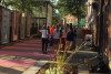 A pedestrian alley in Fitchburg, MA with boxes for artwork to go in, tables, chairs and very bright pink stripes on the walkway.