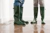 Two people wearing boots on flooded floor 